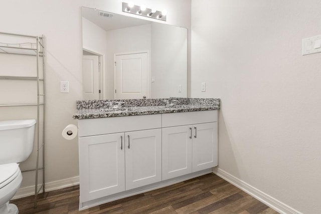 bathroom featuring double vanity, wood finished floors, visible vents, toilet, and baseboards