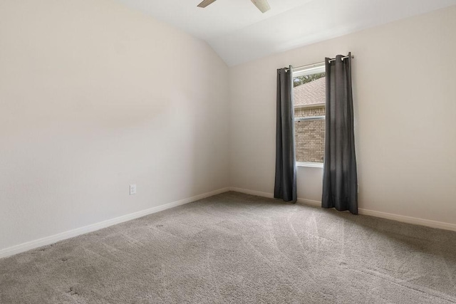 empty room featuring lofted ceiling, carpet floors, baseboards, and ceiling fan