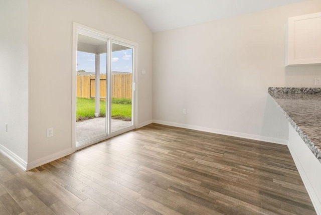 unfurnished dining area with wood finished floors, lofted ceiling, and baseboards