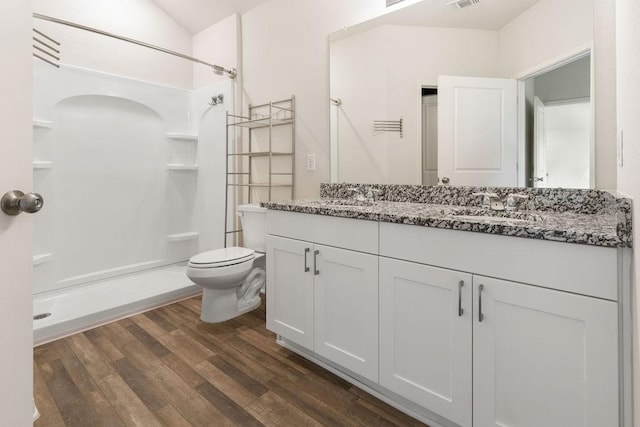 full bath with wood finished floors, toilet, a stall shower, and a sink