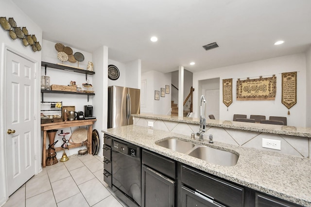 kitchen featuring light stone counters, light tile patterned floors, a sink, freestanding refrigerator, and black dishwasher