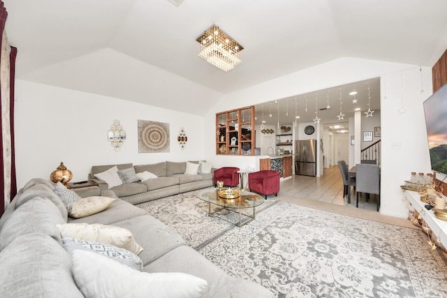 living area featuring stairway, vaulted ceiling, and an inviting chandelier
