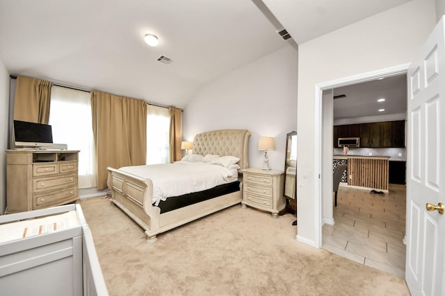 bedroom with light carpet, vaulted ceiling, visible vents, and baseboards