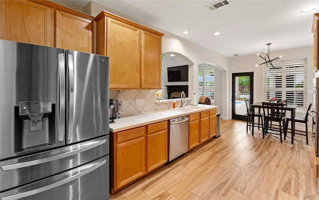 kitchen featuring stainless steel appliances, light countertops, visible vents, a sink, and arched walkways