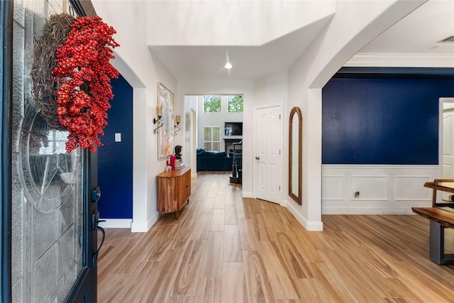 entrance foyer with wainscoting, arched walkways, and light wood-style flooring