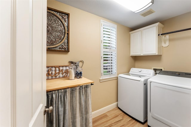 laundry room featuring washing machine and clothes dryer, light wood-style flooring, baseboards, visible vents, and cabinet space