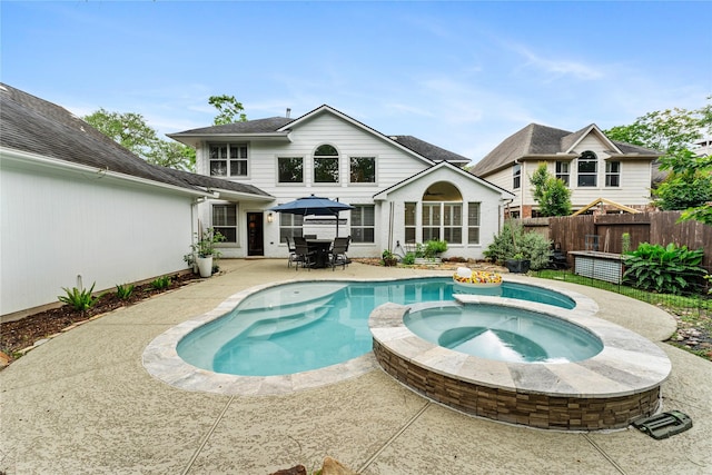 back of property featuring fence, outdoor dining space, a patio, and a pool with connected hot tub
