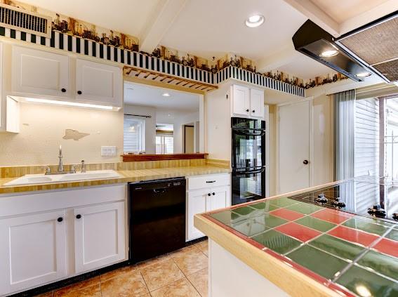 kitchen with plenty of natural light, beam ceiling, a sink, white cabinets, and black appliances