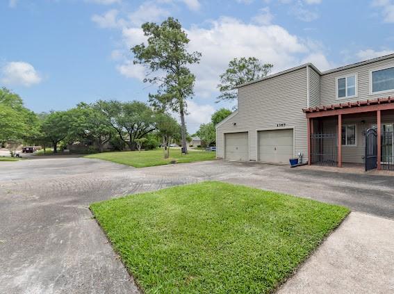 view of property exterior with a yard, an attached garage, and driveway