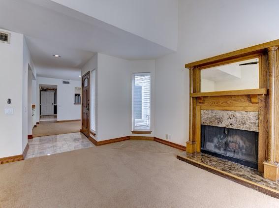 unfurnished living room featuring carpet floors, baseboards, and a tile fireplace