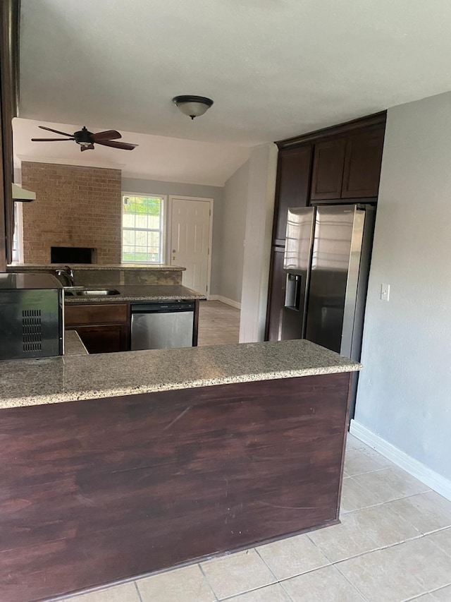 14418 Alkay St, Houston, TX 77045 - kitchen with light stone countertops, dark brown cabinetry, a ceiling fan, baseboards, and appliances with stainless steel finishes