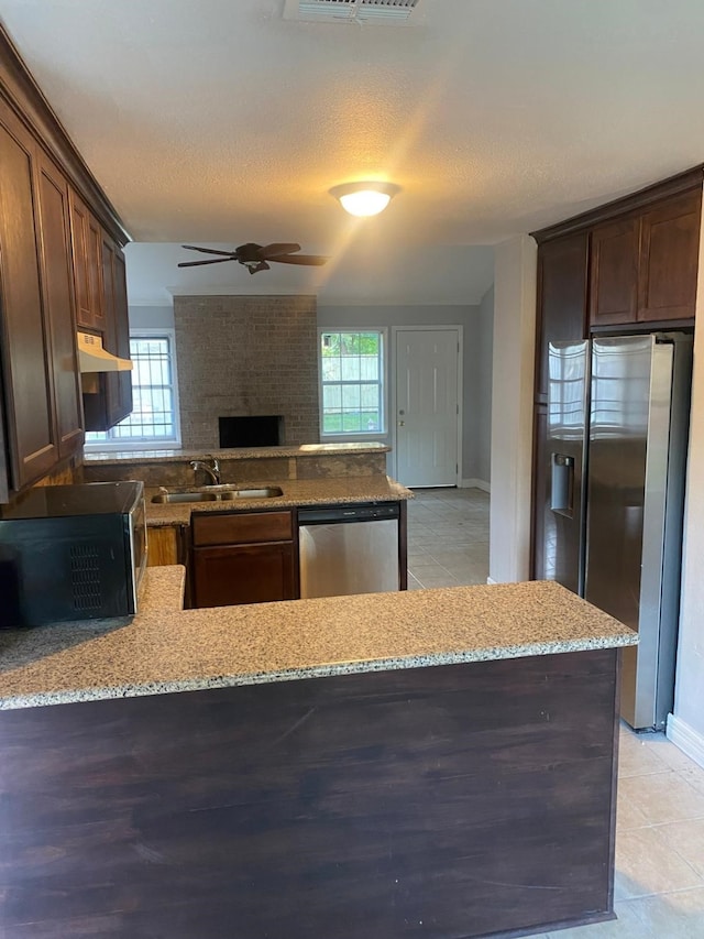 14418 Alkay St, Houston, TX 77045 - kitchen with a sink, stainless steel appliances, under cabinet range hood, light stone counters, and a peninsula