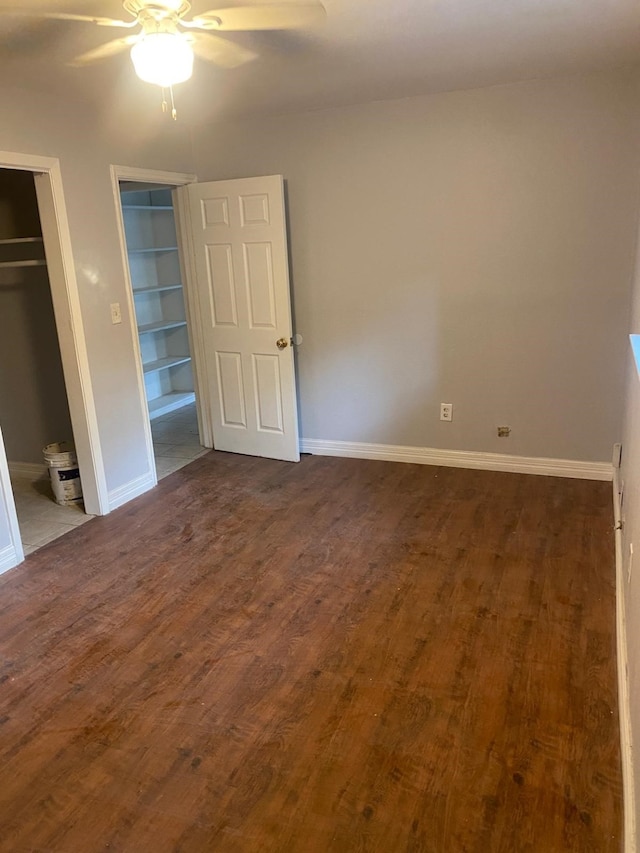 14418 Alkay St, Houston, TX 77045 - unfurnished bedroom with dark wood-type flooring, ceiling fan, two closets, and baseboards