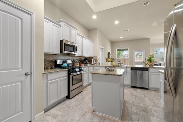 3639 Daintree Park Dr, Katy, TX 77494 - kitchen with appliances with stainless steel finishes, decorative backsplash, a center island, light stone countertops, and recessed lighting