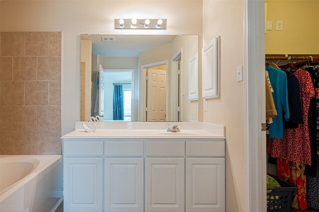 bathroom with a spacious closet, a washtub, and vanity