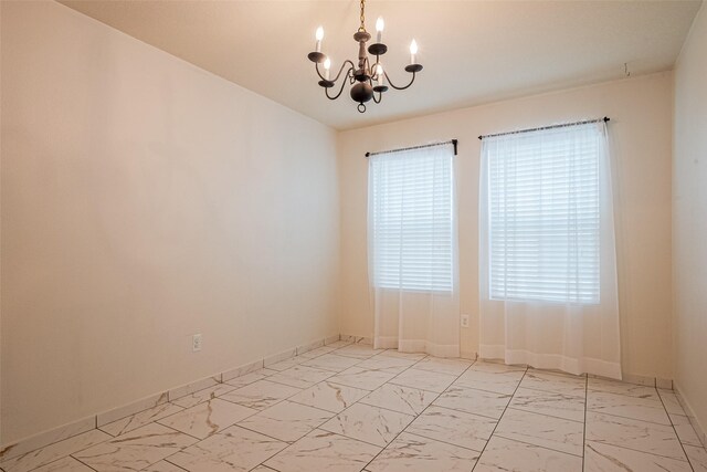 empty room featuring baseboards, marble finish floor, and a notable chandelier