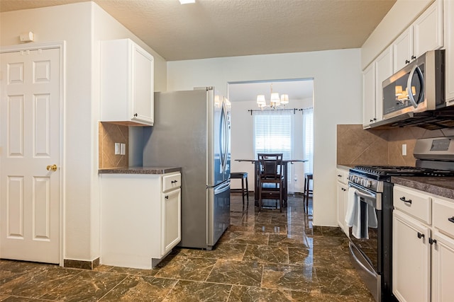kitchen with dark countertops, tasteful backsplash, appliances with stainless steel finishes, and an inviting chandelier