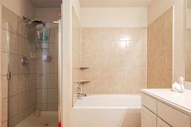 bathroom featuring vanity, a bathtub, and a tile shower