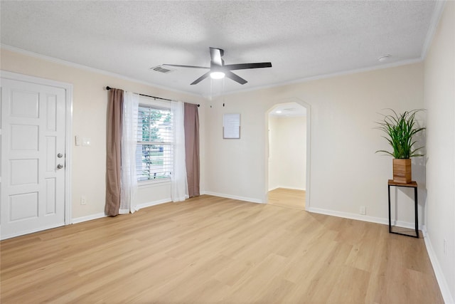 unfurnished room with a textured ceiling, a ceiling fan, light wood-style floors, arched walkways, and ornamental molding