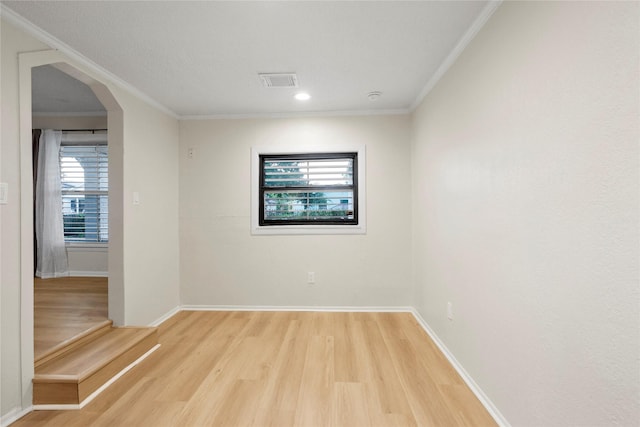 spare room with ornamental molding, light wood-type flooring, arched walkways, baseboards, and recessed lighting