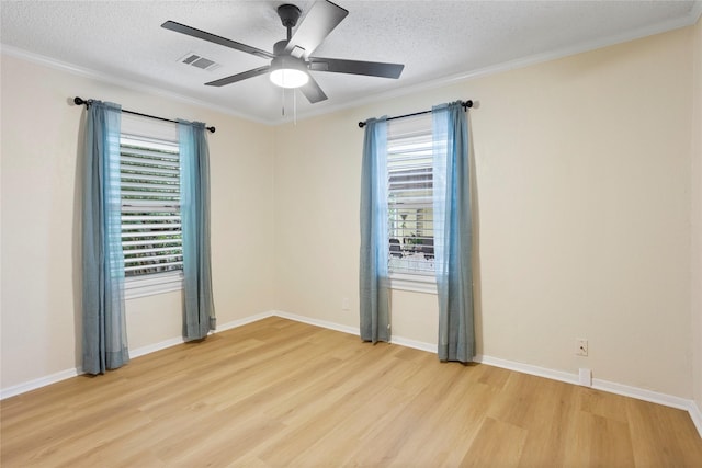spare room with plenty of natural light, light wood finished floors, a textured ceiling, ornamental molding, and a ceiling fan