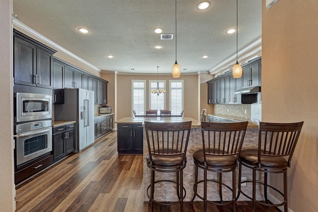kitchen with crown molding, dark wood finished floors, appliances with stainless steel finishes, visible vents, and recessed lighting