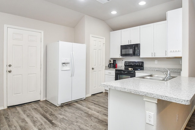 kitchen featuring light wood finished floors, a peninsula, a sink, light countertops, and black appliances