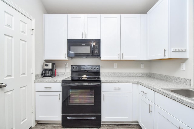 kitchen with black appliances, white cabinets, and light countertops