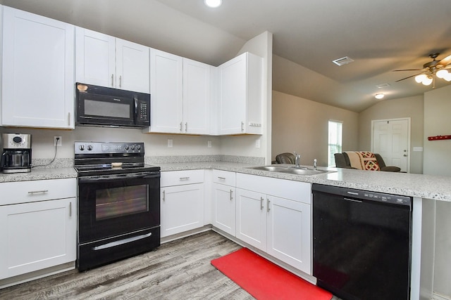 kitchen featuring a peninsula, a sink, lofted ceiling, light countertops, and black appliances
