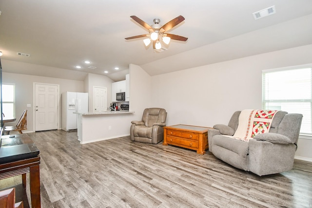 living room with lofted ceiling, wood finished floors, visible vents, baseboards, and ceiling fan
