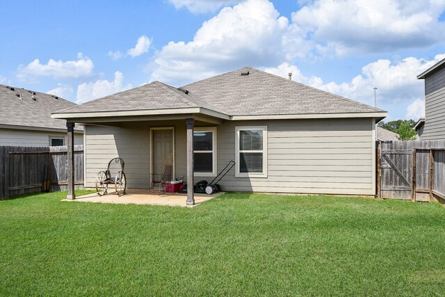 rear view of property with a yard, a patio area, roof with shingles, and a fenced backyard
