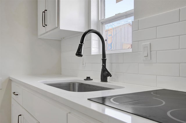 4716 Siegel St, Houston, TX 77009 - room details with a sink, white cabinetry, black electric cooktop, decorative backsplash, and light stone counters