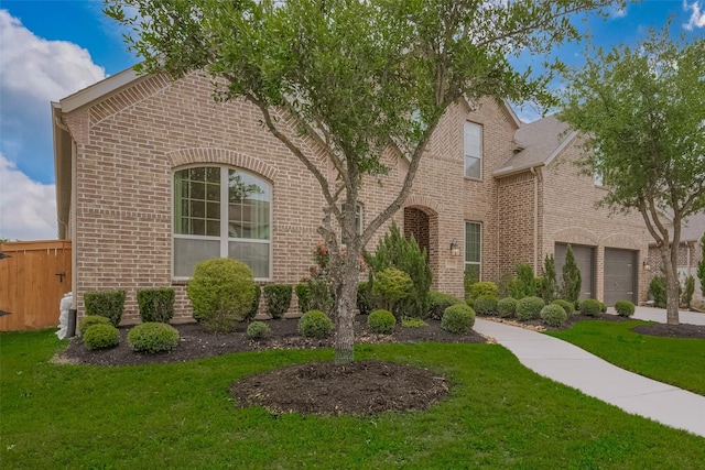 view of front of house featuring driveway, fence, brick siding, a garage, and a front yard