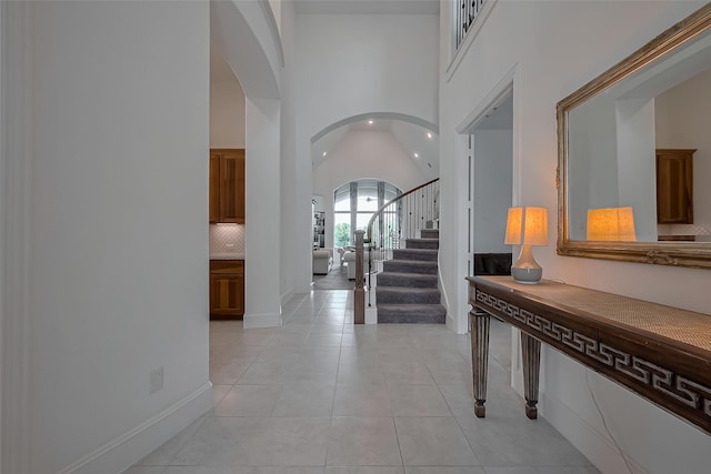 foyer with arched walkways, recessed lighting, stairway, high vaulted ceiling, and light tile patterned floors