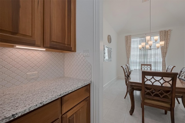 dining room with light tile patterned flooring, vaulted ceiling, baseboards, and a notable chandelier