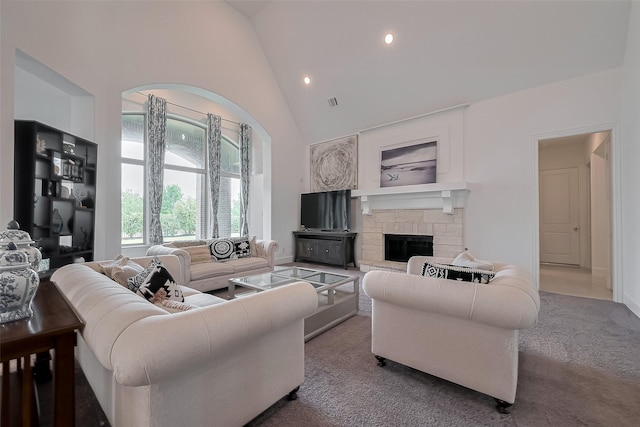 living area featuring high vaulted ceiling, a stone fireplace, carpet floors, visible vents, and recessed lighting