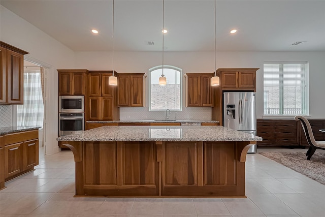 kitchen with backsplash, visible vents, a sink, a center island, and appliances with stainless steel finishes