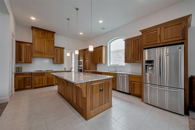 kitchen featuring tasteful backsplash, brown cabinets, stainless steel appliances, light stone countertops, and a kitchen island