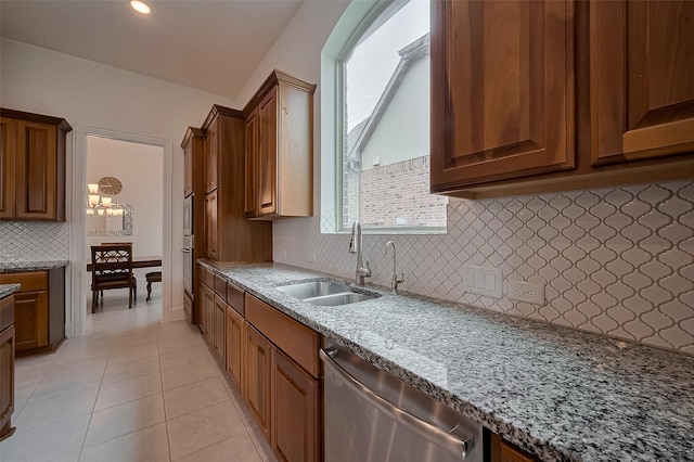 kitchen with dark stone counters, a sink, light tile patterned floors, backsplash, and appliances with stainless steel finishes