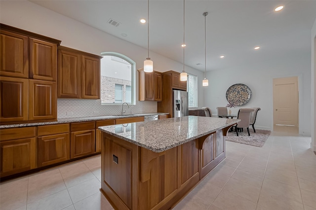 kitchen featuring tasteful backsplash, light stone counters, light tile patterned flooring, appliances with stainless steel finishes, and visible vents