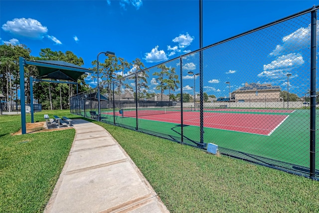 view of tennis court featuring fence and a yard