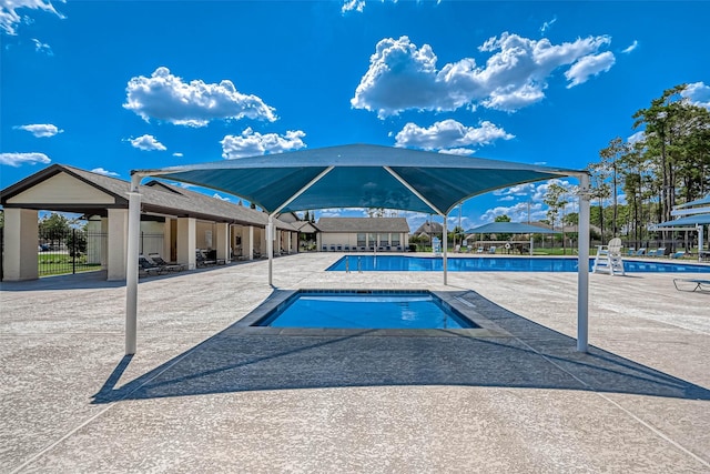 pool with fence, a patio area, and a hot tub