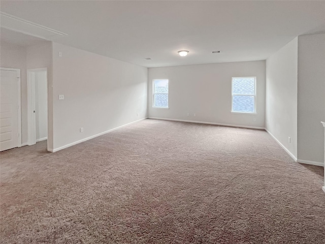 spare room with carpet floors, visible vents, and baseboards