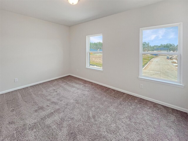 unfurnished room featuring carpet and baseboards
