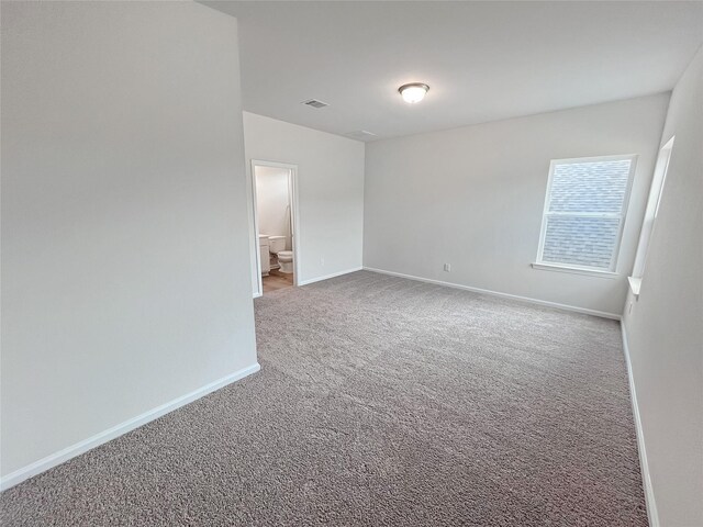 spare room featuring baseboards, visible vents, and carpet