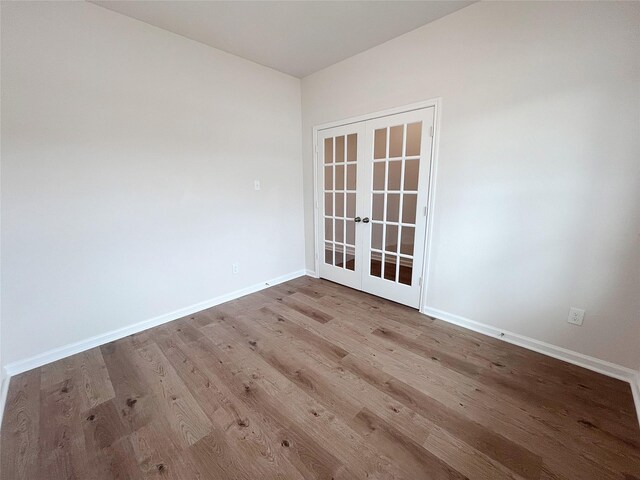 unfurnished room featuring baseboards, french doors, and wood finished floors