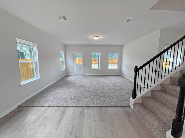 carpeted foyer with wood finished floors, visible vents, and baseboards