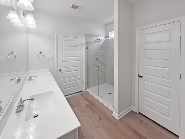 bathroom with a sink, wood finished floors, a stall shower, a notable chandelier, and visible vents