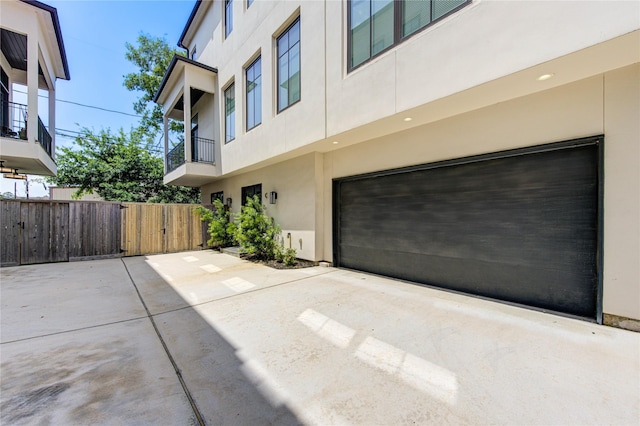 1509 Caywood Ln Unit C, Houston, TX 77055 - view of property exterior featuring stucco siding, a balcony, a garage, fence, and driveway
