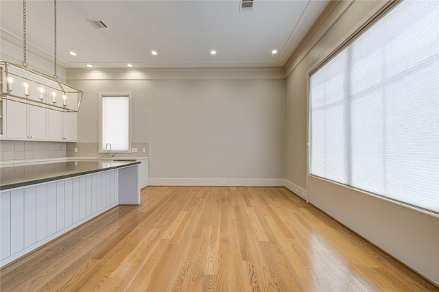 1509 Caywood Ln Unit C, Houston, TX 77055 - kitchen with white cabinetry, backsplash, a sink, ornamental molding, and light wood finished floors